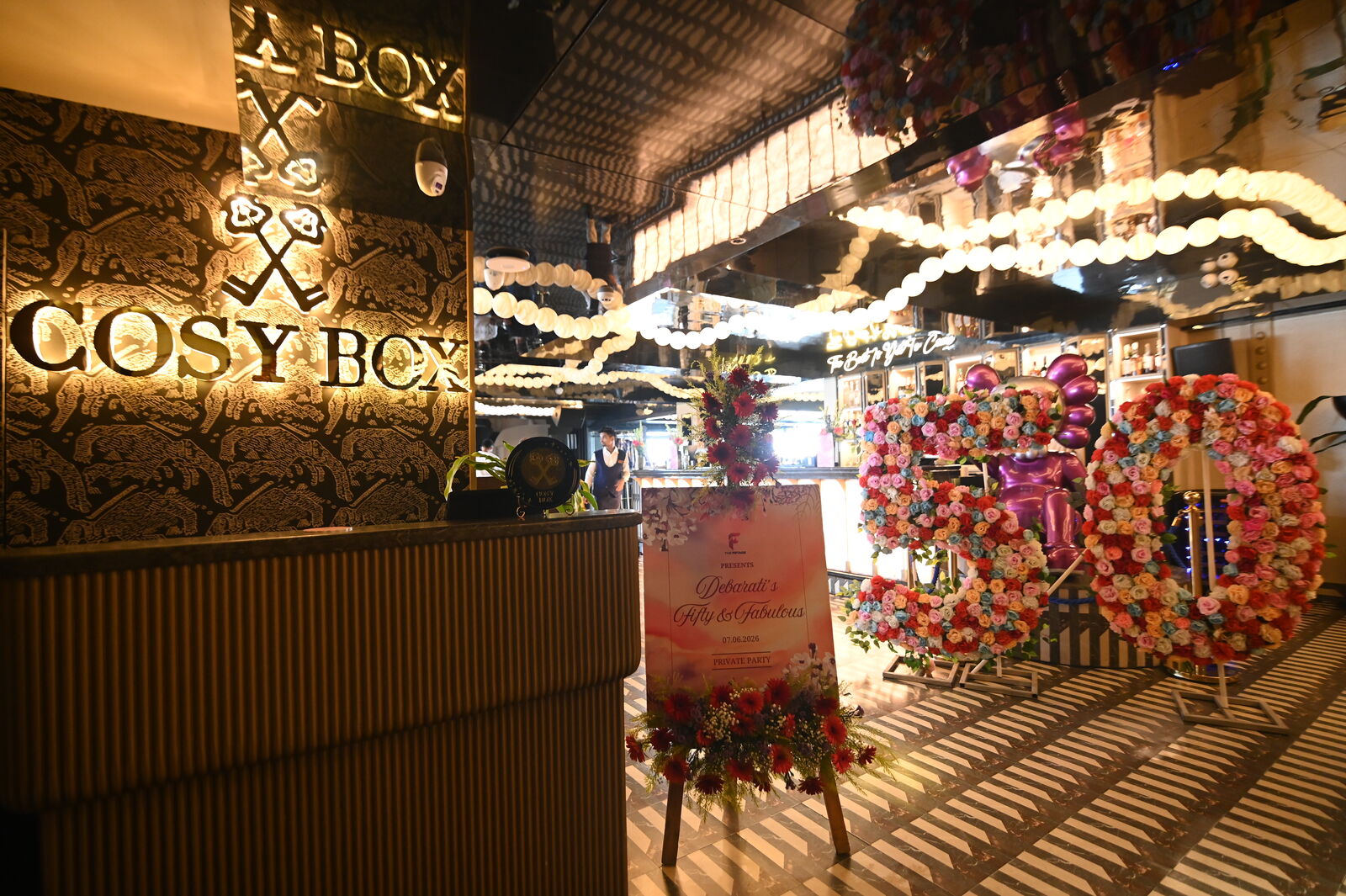 Cosy Box brand signage framed by florals and fairy lights