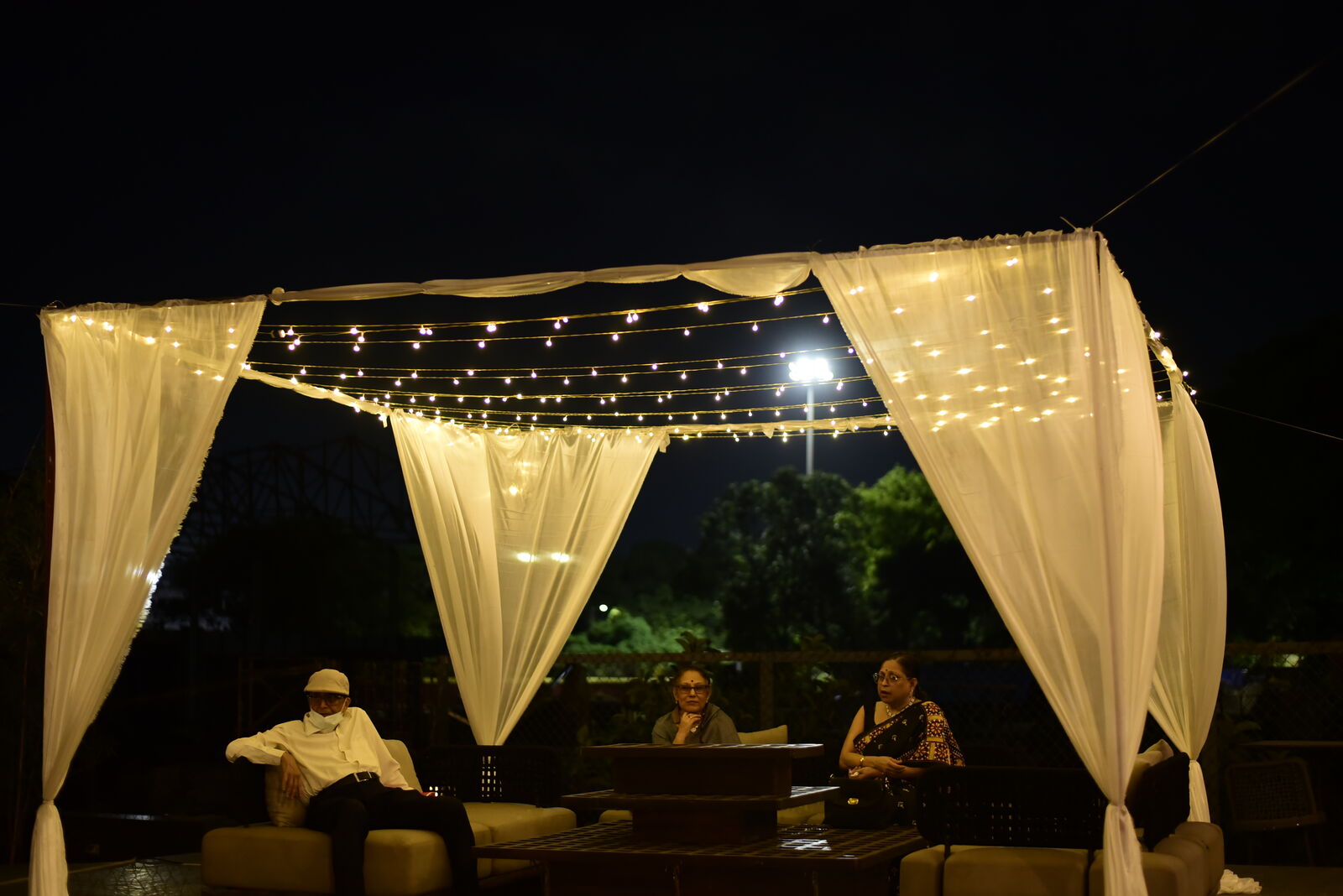 Draped lounge cabana lit with fairy lights at night